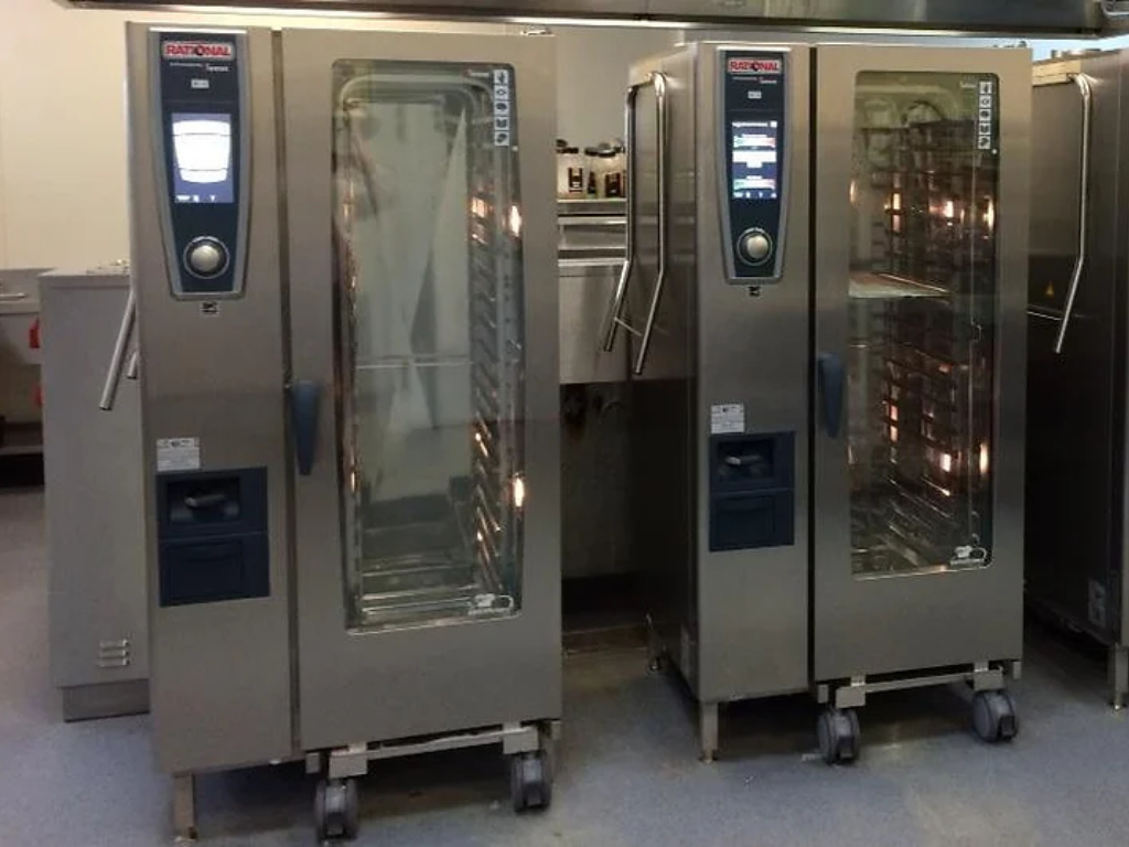 A row of commercial ovens lined up in a bustling commercial kitchen, ready for cooking delicious meals.